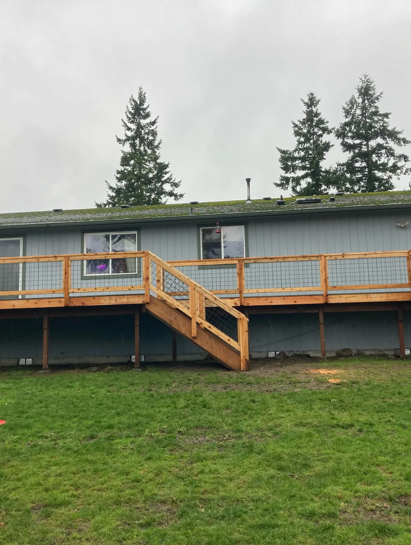 Elevated cedar deck wire panel railing stairs backyard